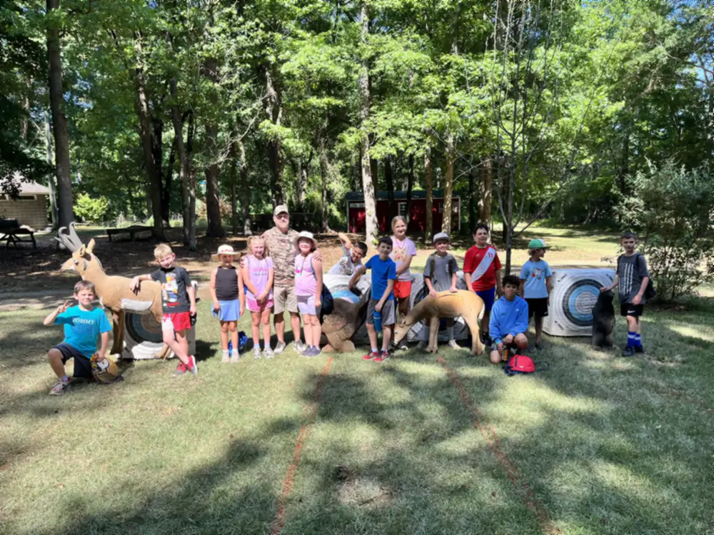Campers packed in around the 3D deer and bear targets on the archery day, one with an arm raised